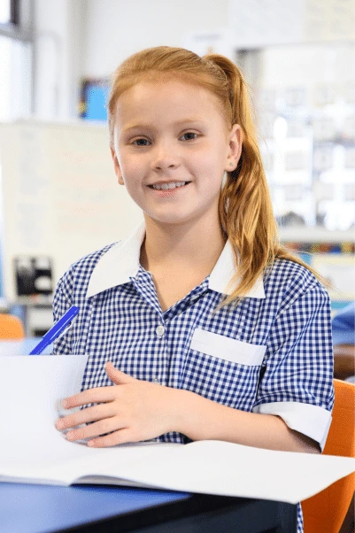A girl in her blue school uniform turning a book page.